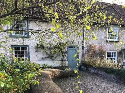 a stone house with a green door and windows at Lavender Cottage in Methwold