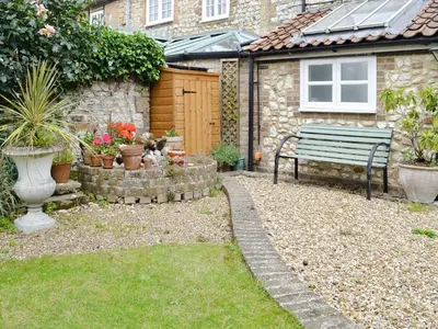 a garden with a bench and some potted plants at Lavender Cottage in Methwold