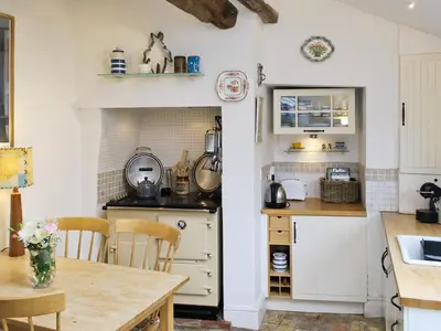 a kitchen with white cabinets and a wooden table at Lavender Cottage in Methwold