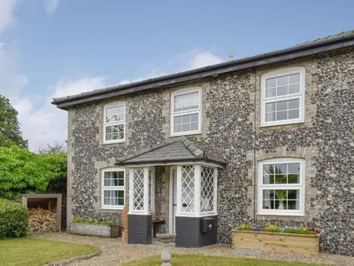 a stone house with white windows and a door at Beck Cottage in Mildenhall