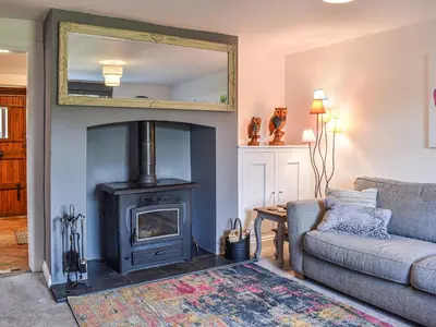 a living room with a fireplace and a couch at Beck Cottage in Mildenhall