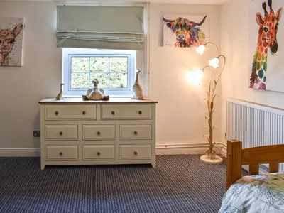 a bedroom with a dresser and a window at Beck Cottage in Mildenhall