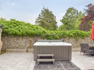 a hot tub and a bench on a patio at Beck Cottage in Mildenhall