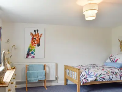 a bedroom with a bed and a painting of a giraffe at Beck Cottage in Mildenhall