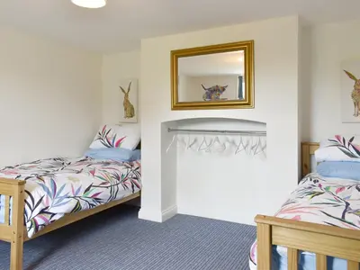 a bedroom with two beds and a mirror at Beck Cottage in Mildenhall