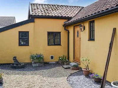 a yellow house with potted plants in front of it at Bradcar Farm Cottage in Snetterton