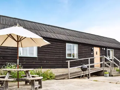 a house with a table and an umbrella and a bench at The Long Barn in Chelmsford