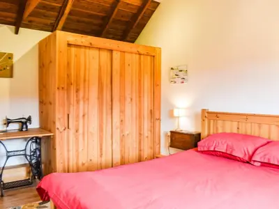 a bedroom with a red bed and a wooden wall at The Long Barn in Chelmsford