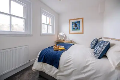 a bedroom with a bed with a blue blanket and two windows at The Art Room, Leiston in Leiston
