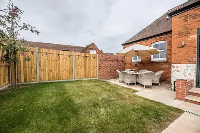 a backyard with a wooden fence and a table with an umbrella at The Art Room, Leiston in Leiston