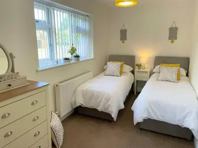 a bedroom with two beds and a mirror at Stylish Boutique Bungalow in Felixstowe
