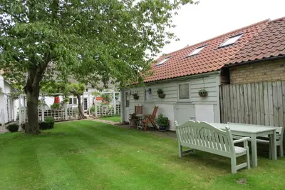 a bench in a yard next to a house at The Old Stables, Whitehall Farmhouse, Oakington in Cambridge