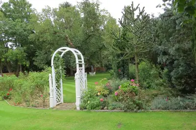 a white gate in a garden with flowers at The Old Stables, Whitehall Farmhouse, Oakington in Cambridge