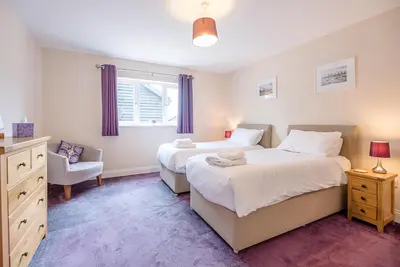 a bedroom with two beds and a chair and a window at Grove Farm Bungalow with swimming pool, Dallinghoo in Woodbridge