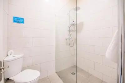 a bathroom with a toilet and a glass shower at Grove Farm Bungalow with swimming pool, Dallinghoo in Woodbridge