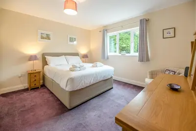 a bedroom with a bed and a table and a window at Grove Farm Bungalow with swimming pool, Dallinghoo in Woodbridge