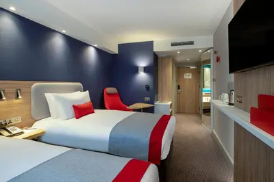 a hotel room with two beds and a tv at Holiday Inn Express Cambridge West - Cambourne by IHG in Cambridge