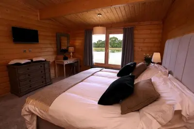 a bedroom with a large bed and a window at Cambridgeshire Lakes - luxury lodges in a stunning lake location in Gamlingay