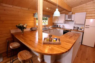a kitchen with a large wooden table in a cabin at Cambridgeshire Lakes - luxury lodges in a stunning lake location in Gamlingay