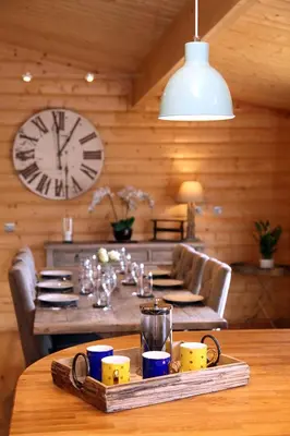a dining room with a table with a clock on the wall at Cambridgeshire Lakes - luxury lodges in a stunning lake location in Gamlingay