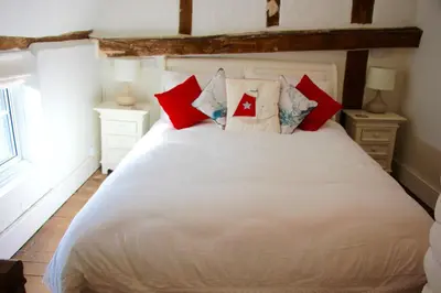 a bedroom with a white bed with red pillows at Romantic* Castle on the Hill Cottage *Framlingham in Framlingham