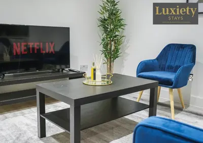 a living room with a table and two blue chairs at Stylish 1BR By Luxiety Stays Short Lets & Serviced Accommodation Southend on sea - Near High St & Southend Beach in Southend-on-Sea