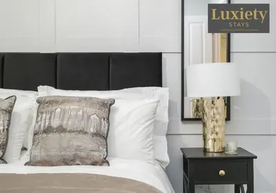 a bed with white pillows and a lamp on a table at Stylish 1BR By Luxiety Stays Short Lets & Serviced Accommodation Southend on sea - Near High St & Southend Beach in Southend-on-Sea