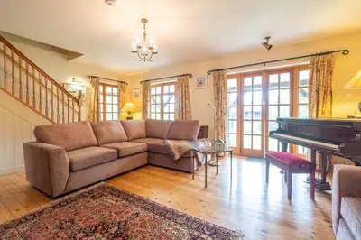 a living room with a couch and a piano at Micawbers - Aldeburgh Coastal Cottages in Thorpeness