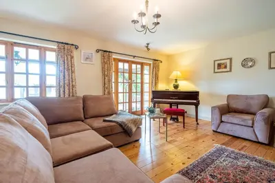 a living room with a couch and a piano at Micawbers - Aldeburgh Coastal Cottages in Thorpeness