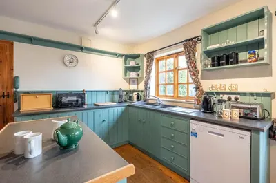 a kitchen with green cabinets and a counter top at Micawbers - Aldeburgh Coastal Cottages in Thorpeness