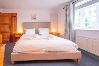 a bedroom with a large white bed with two towels on it at Micawbers - Aldeburgh Coastal Cottages in Thorpeness
