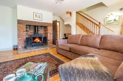 a living room with a couch and a fireplace at Micawbers - Aldeburgh Coastal Cottages in Thorpeness