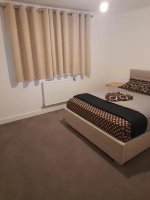 a bedroom with a bed and a window with curtains at Beautiful Double Bedroom- In a modern 2 bed shared house in Chigwell