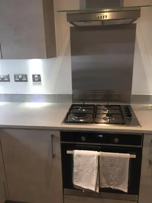 a kitchen with a stove top oven with two white towels at Beautiful Double Bedroom- In a modern 2 bed shared house in Chigwell