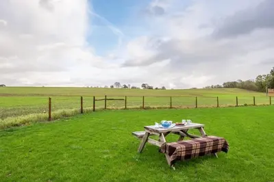 a picnic table in the middle of a field at Maltings Lodge in Chelsworth