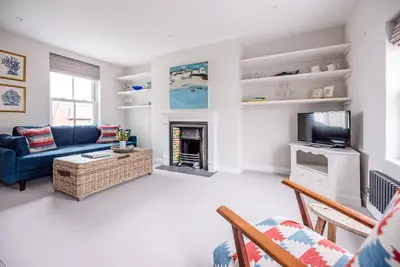 a living room with a blue couch and a tv at Pebble View, Aldeburgh in Aldeburgh