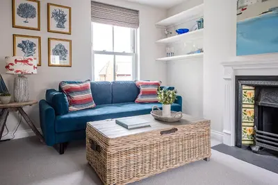 a living room with a blue couch and a fireplace at Pebble View, Aldeburgh in Aldeburgh