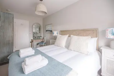 a bedroom with a large white bed with towels on it at Pebble View, Aldeburgh in Aldeburgh