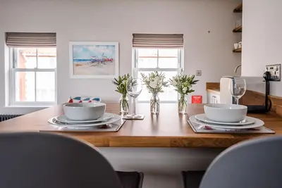 a dining room table with two bowls and plates on it at Pebble View, Aldeburgh in Aldeburgh