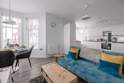 a living room with a blue couch and a kitchen at 4 Buregate House, Felixstowe in Felixstowe