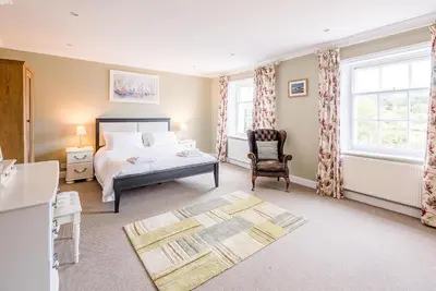 a bedroom with a bed and a chair and windows at 4 Market Cross House, Aldeburgh in Aldeburgh