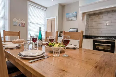 a wooden table with wine glasses and a bowl of food at 4 Market Cross House, Aldeburgh in Aldeburgh