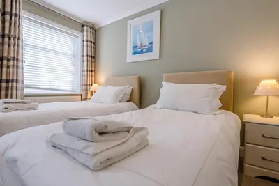 a bedroom with two beds with white sheets and a window at 4 Market Cross House, Aldeburgh in Aldeburgh