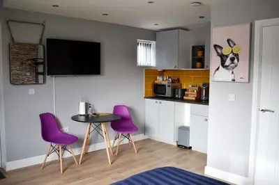 a kitchen with purple chairs and a small table at Modern Luxury 1 bed apartment with parking near Stansted Airport in Stansted Mountfitchet
