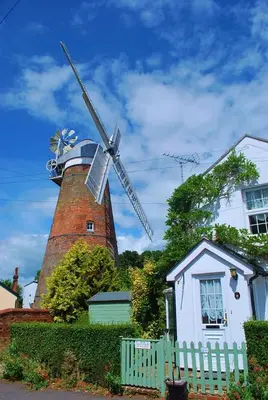 a windmill in front of a house with a white fence at Modern Luxury 1 bed apartment with parking near Stansted Airport in Stansted Mountfitchet
