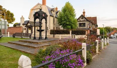 a house with a fence and flowers in front of it at Modern Luxury 1 bed apartment with parking near Stansted Airport in Stansted Mountfitchet