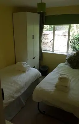 two beds in a room with a window at Entire Thatched Cottage in Melbourn