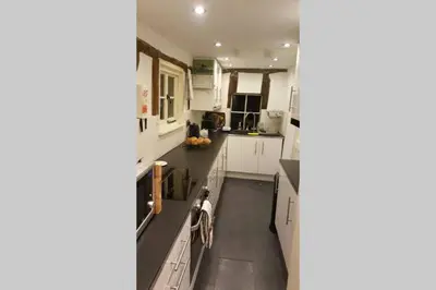 a kitchen with white cabinets and a black counter top at Entire Thatched Cottage in Melbourn
