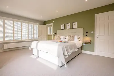 a bedroom with a white bed and green walls at Festival House, Snape in Saxmundham
