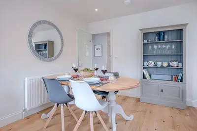 a dining room with a table and chairs and a mirror at Festival House, Snape in Saxmundham
